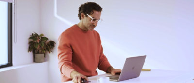 A man standing and working on the laptop.