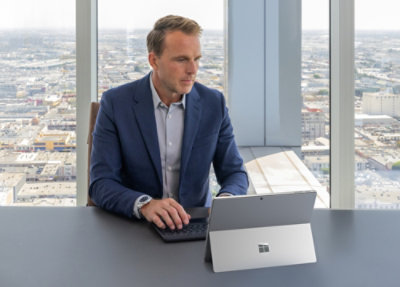 A person in a suit sitting at a desk with a laptop.