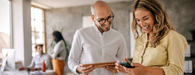 Twee mensen kijken naar de mobiele telefoon en lachen.