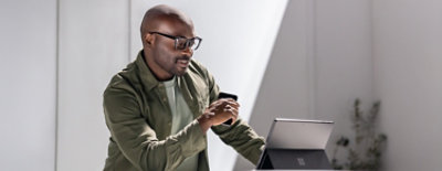 Een persoon die naar het tabblad kijkt en een mobiel in zijn hand vasthoudt.