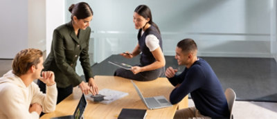 A group of people sitting around a table, with one person using a mouse.