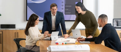 A group of people sitting around a table with a laptop.