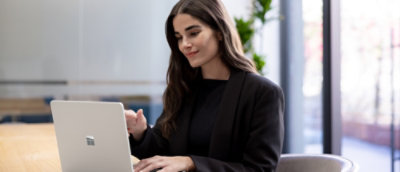 A woman in a black suit looking at a laptop.