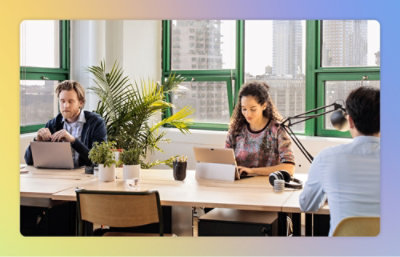 A group of people sitting at a table with laptops and other items.