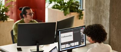 A woman sitting at a desk looking at a computer screen.
