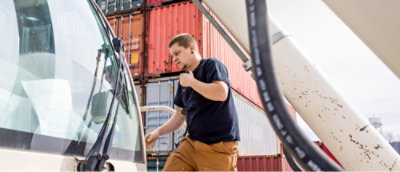 A man in a black shirt standing next to a truck.