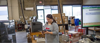 A woman holding a phone in a warehouse.