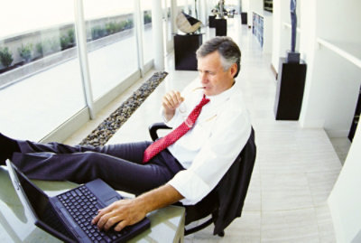 a man in a white suit sitting at a table using a laptop