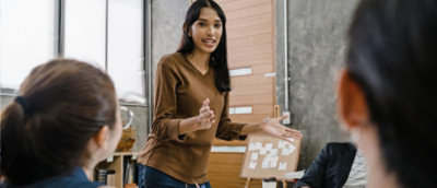 A woman in a brown shirt pointing at something.