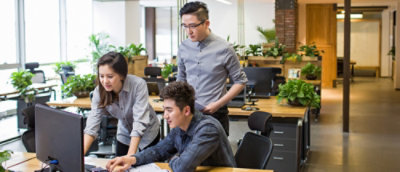 A group of people working on a computer in an office.