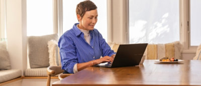 A person sitting at a table typing on a laptop.