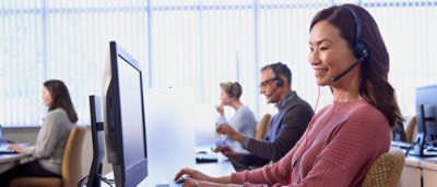 A group of people working at desks with computers and headsets.