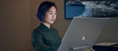 A person wearing a green shirt looking at a computer screen.