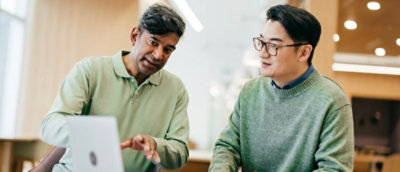 Two people looking at laptop in an office.