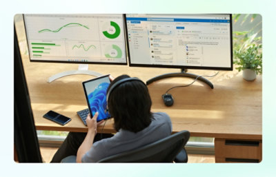 Person at desktop computer with two monitors looking at tablet device