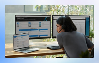 A person working on laptop and two monitors