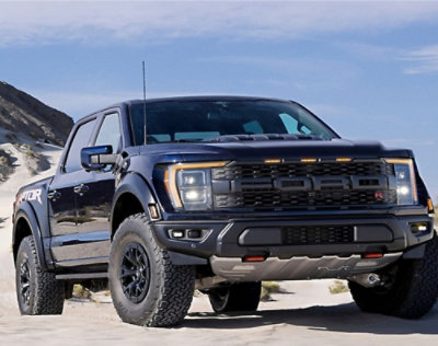 A yellow Volkswagen van parked on a coastal road at sunset with three people sitting and talking in the background.