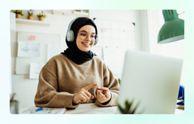 A person wearing headphones pointing at a computer screen.