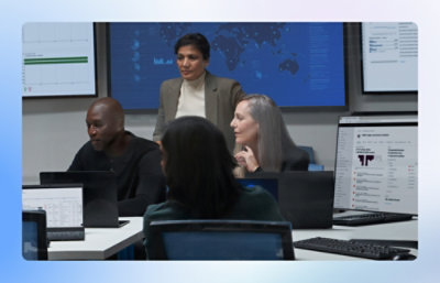 A group of people in a high-tech office with multiple screens displaying graphs and data.
