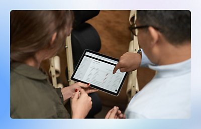 Person showing another person a table on a tablet, pointing