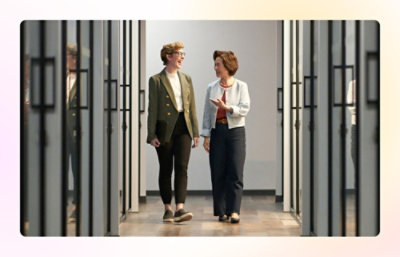 Two people walking in an office hallway talking.