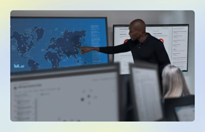 Presenter pointing to a world‑map dashboard on a large display.