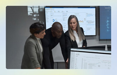 Group of people standing while discussing what they see on computer monitors