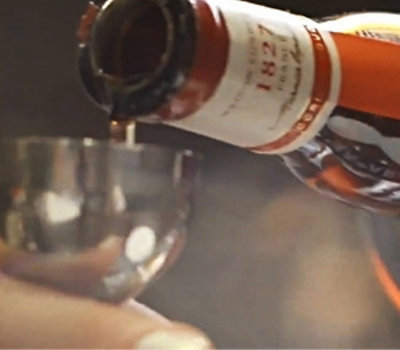 Close-up of a bottle pouring liquid into a metal cup
