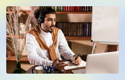 Person wearing headphones and taking notes during an online session.