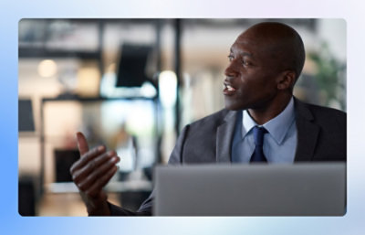 A man in a suit gesture while speaking in an office.