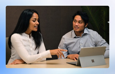 Two colleagues collaborating at a table using a Surface laptop