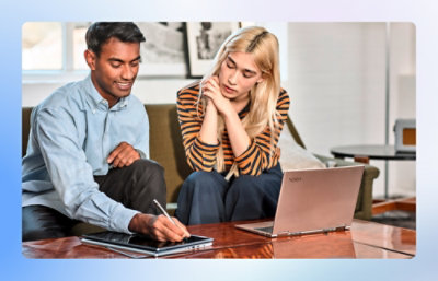A man and woman looking at a laptop on a table.