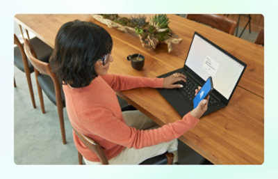 Person using a laptop and mobile phone at a table