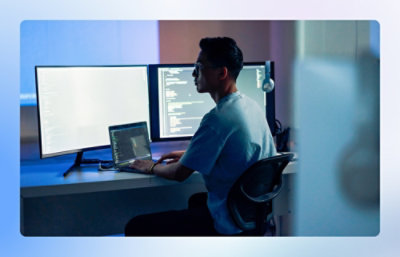 A man working at a desk with a laptop and computer screens