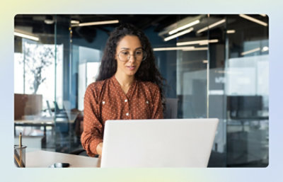 Person working on a laptop in a glass‑walled office