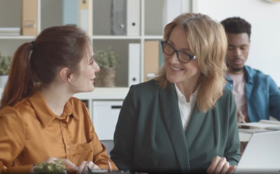 Team members collaborating at desk with laptop.