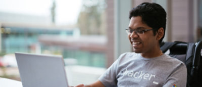 En man som ler och använder en bärbar dator.