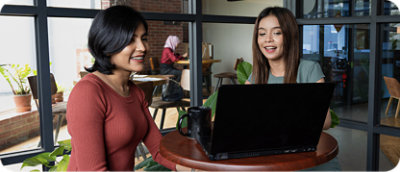 O femeie cu păr lung care se uită la un laptop de pe masă.