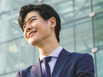 Business professional in a suit standing outside a modern glass office building.