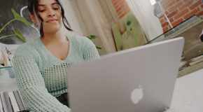 A young woman sitting on her laptop in a living room.