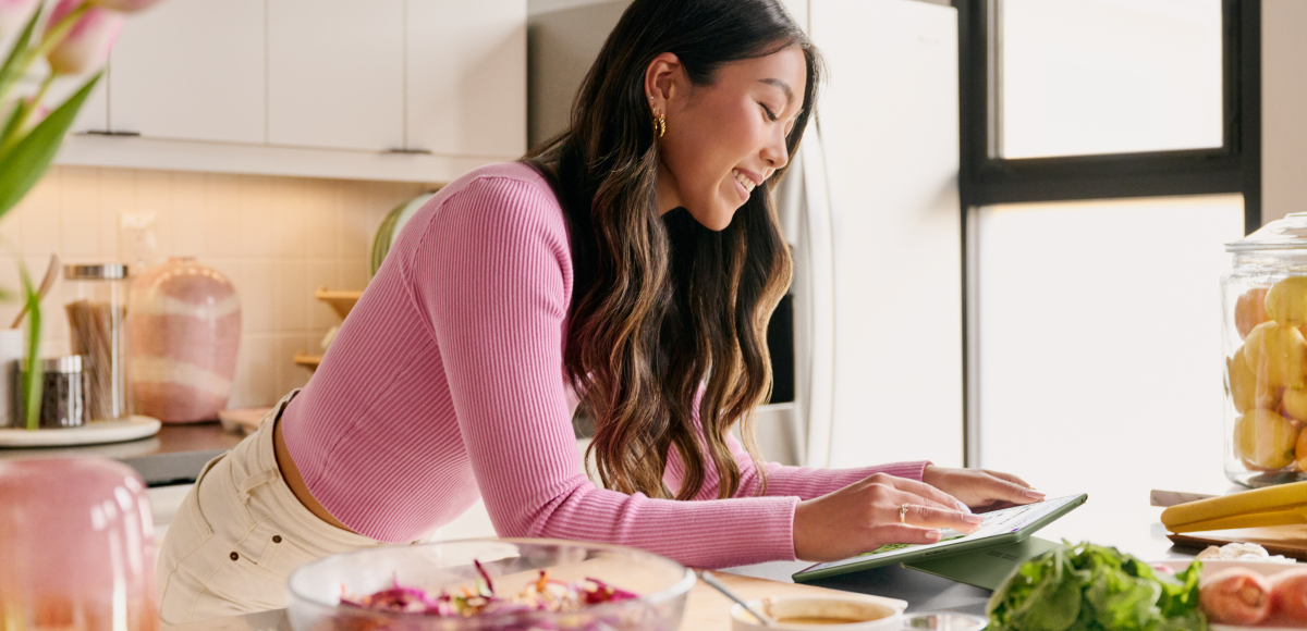 Contextual image of female inside kitchen looking at a recipe on Surface Pro 9 Forest while cooking.