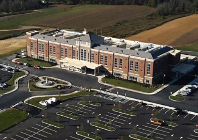 Aerial view of a large modern building with surrounding parking lots and landscaped grounds.
