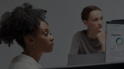 Two people sitting at a desk with a computer monitor displaying a circular chart.
