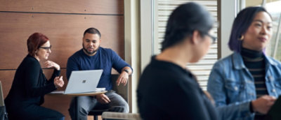 Two people working on laptop and two people discussing something