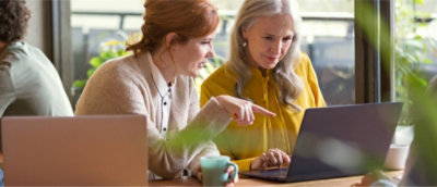 A person pointing at a computer and other one is watching