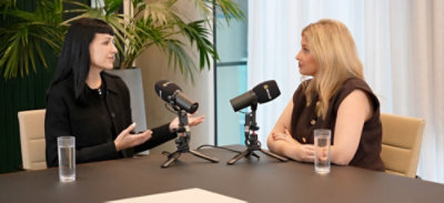 Two speakers discuss cybersecurity topics across a table with microphones in a professional recording studio.
