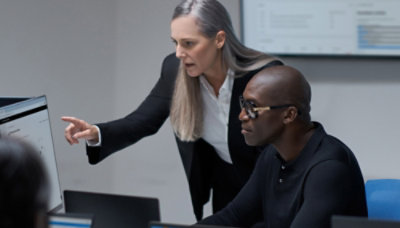 A man and woman looking at a laptop screen.