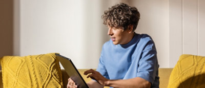 A man sitting on a couch, holding a tablet.