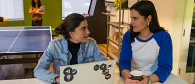  A couple of people are sitting in front of a laptop, having a chat.