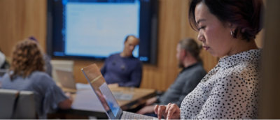 A woman uses a laptop while standing in the foreground